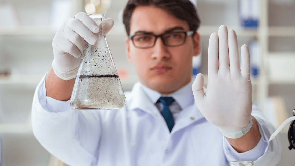 Scientist holding a beaker of water containing total dissolved solids present in water