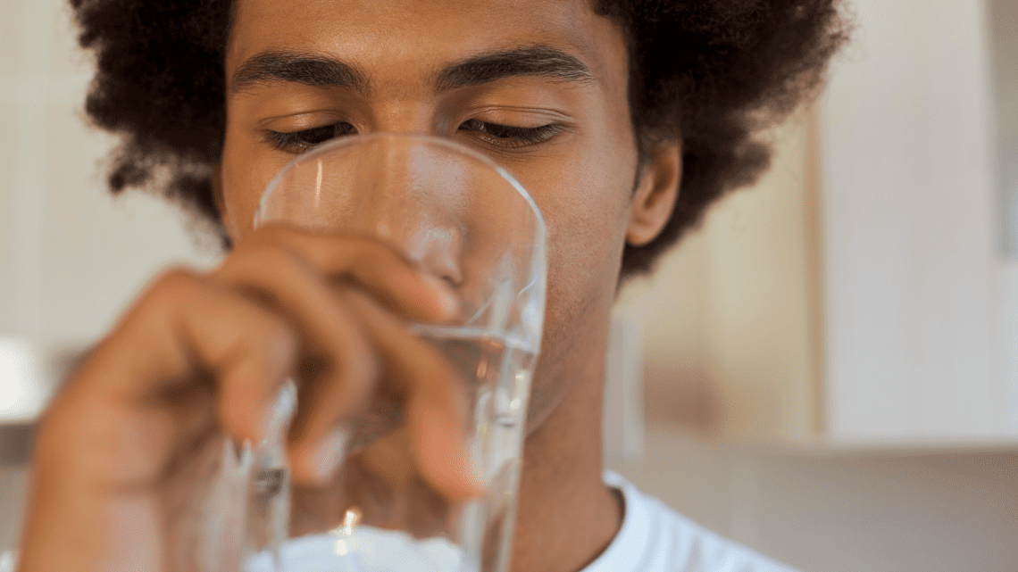 Man drinking a glass of water purified with a water filtration system